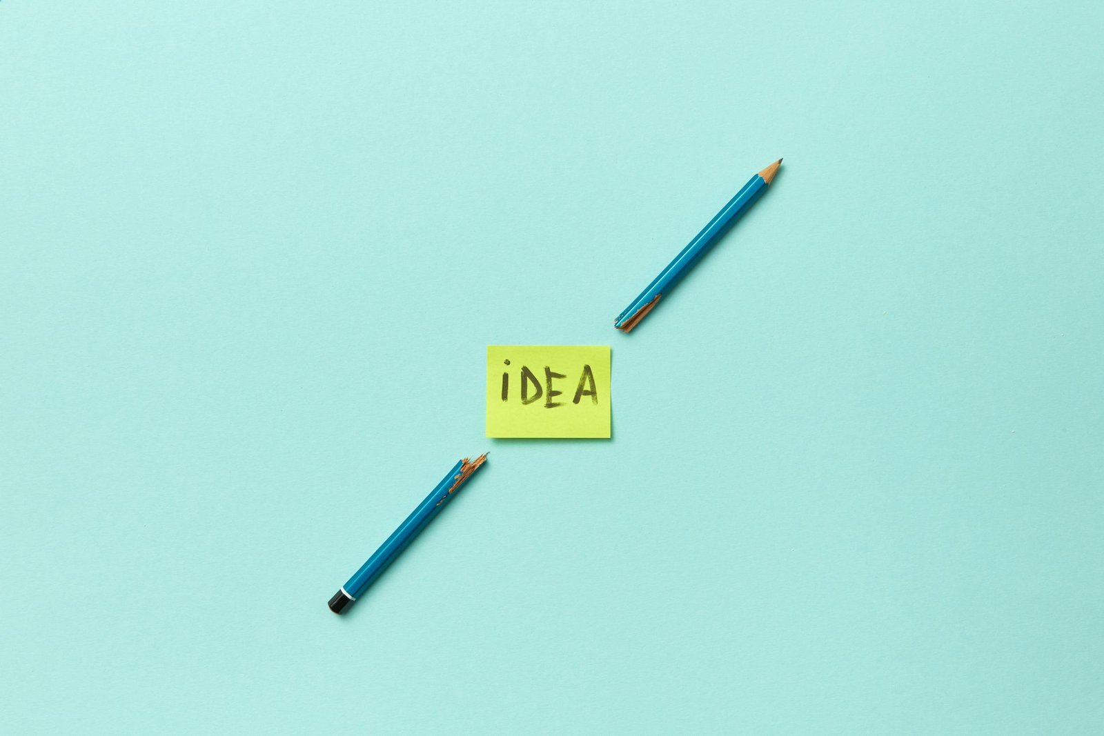 Conceptual photo of a broken pencil with a sticky note labeled 'idea' on a blue background.